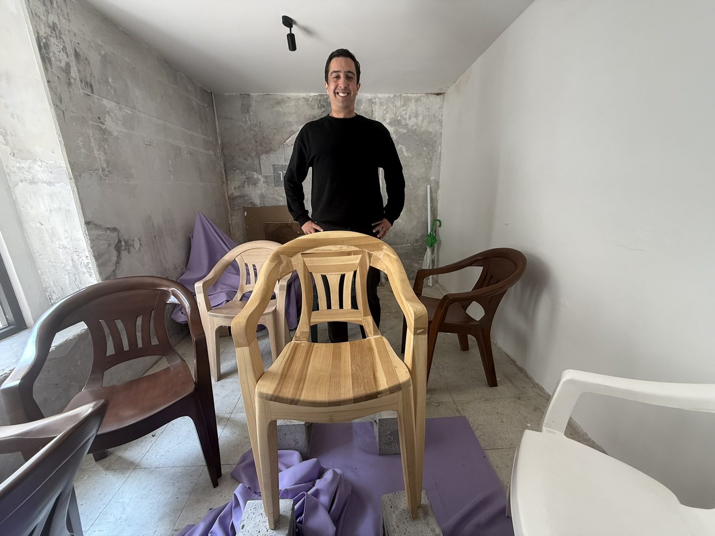 Vicente of HEV.I in his Mexico City studio behind a monobloc armchair made in solid wood, surrounded by plastic monoblocs